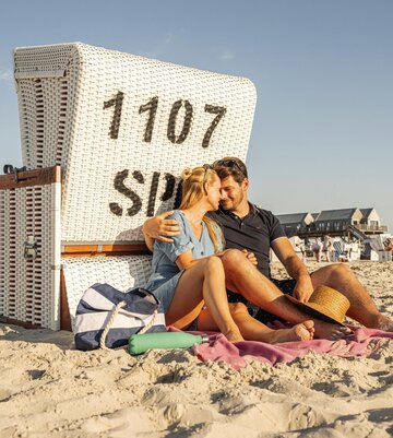 verliebtes Paar vor Strandkorb im Sand