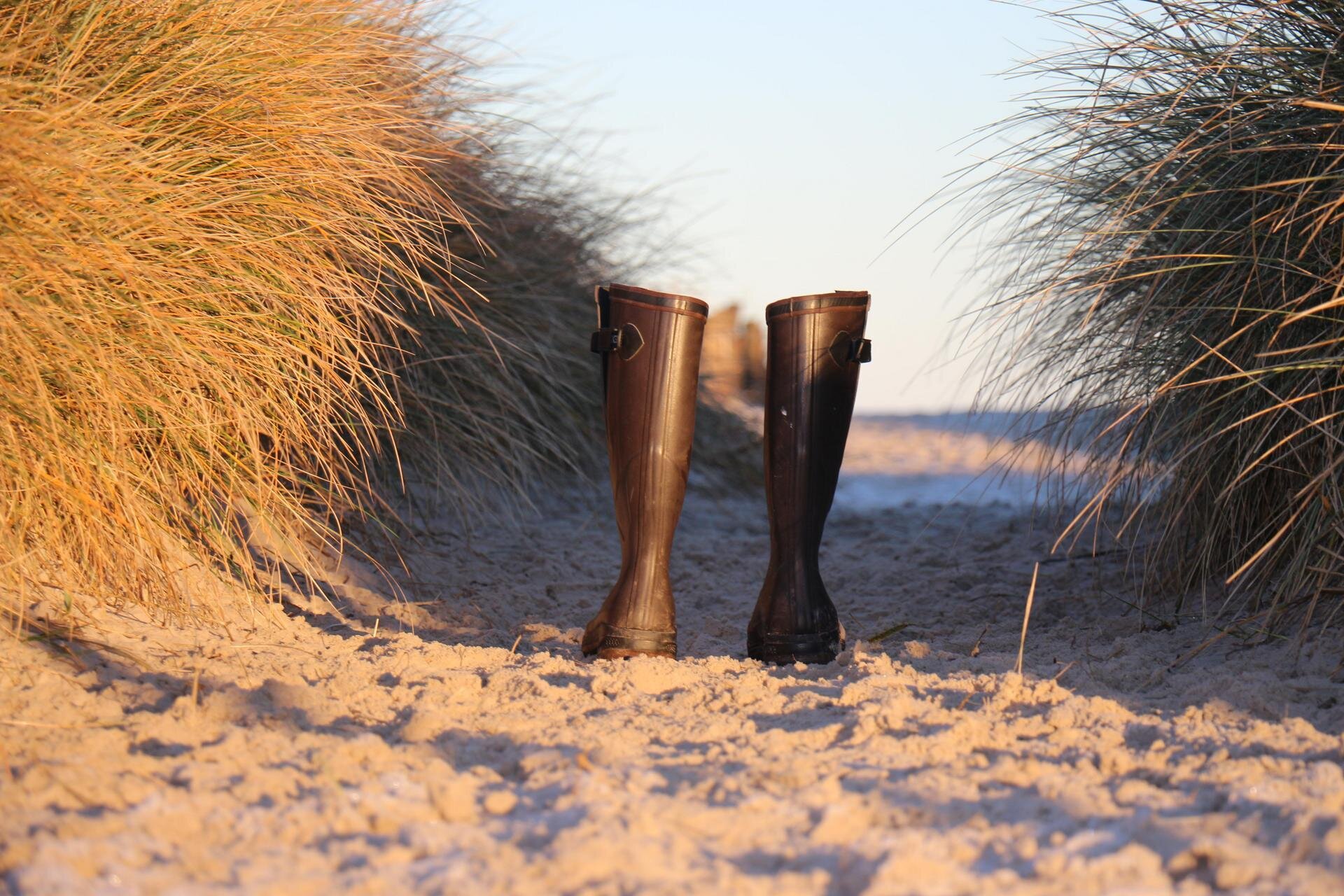 ein Paar Gummistiefel in den Dünen