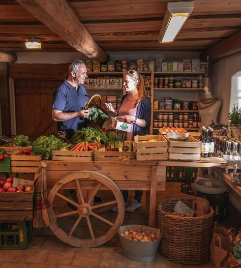 A couple standing in front of fresh vegetables at the farm stand