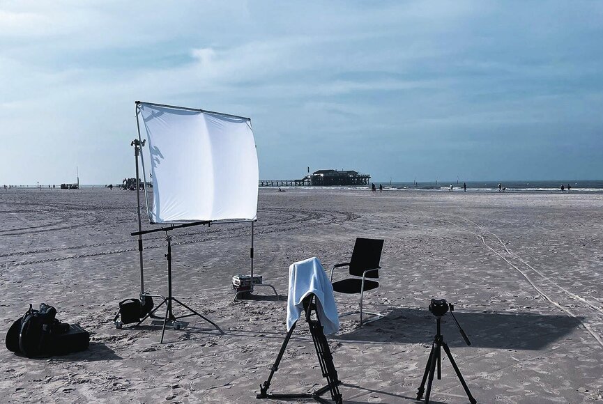 weiße Leinwand, Kamerastativ und ein Stuhl auf dem weiten Sandstrand