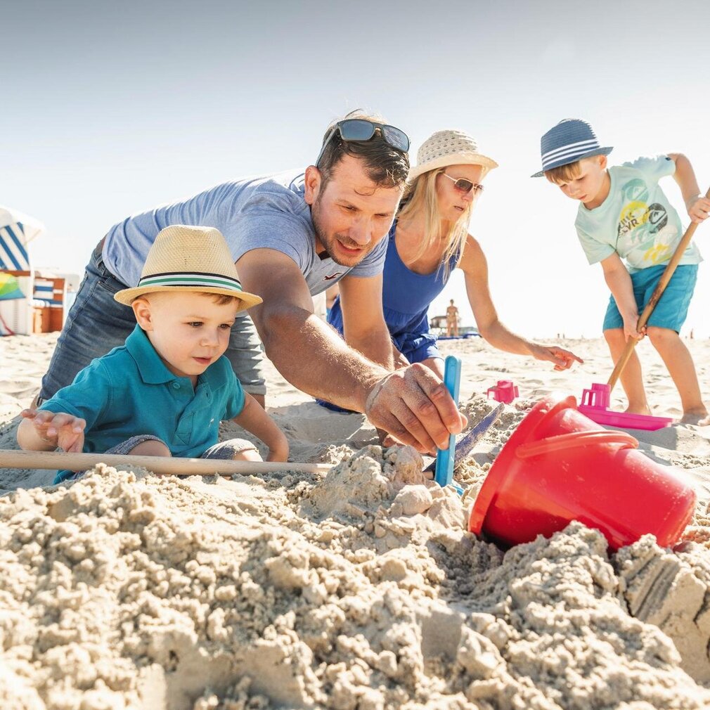 Familie baut eine Sandburg am Strand