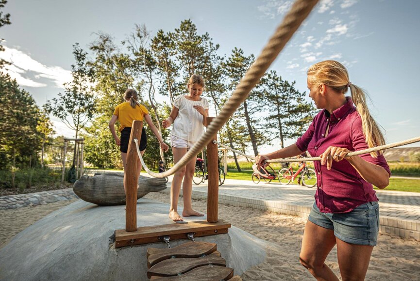 Familie spielt auf Hängebrücke am Seehund-Spielplatz