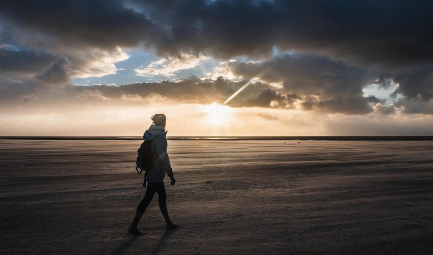 Frau spaziert am Abend am Strand
