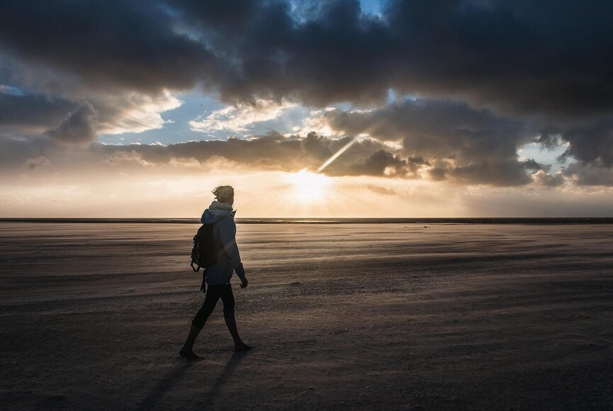 Frau beim Strandspaziergang bei Sonnenuntergang im Herbst