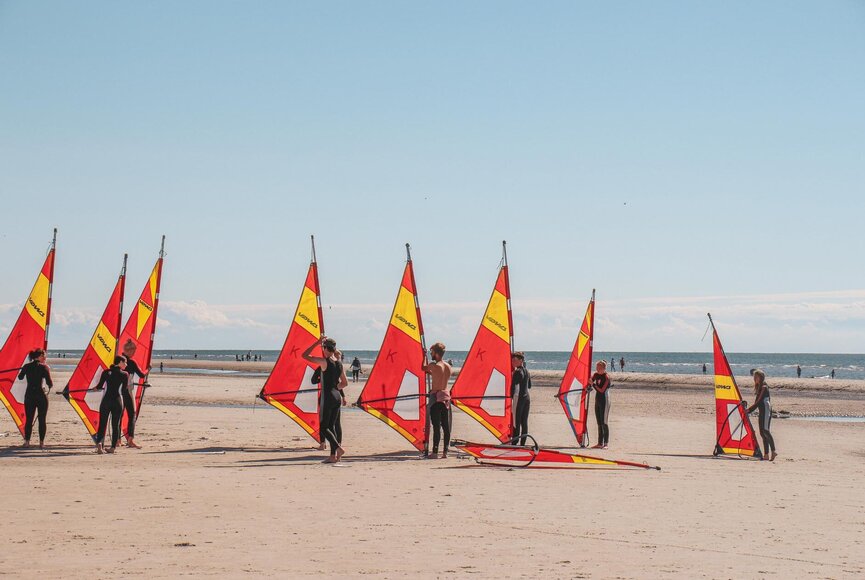 Ein Windsurf-Unterricht am Wasser, bei dem Anfänger lernen die ersten Technicken am Strand lernen