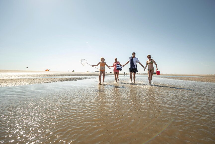 Familie in Badeklamotten an der Wasserkante