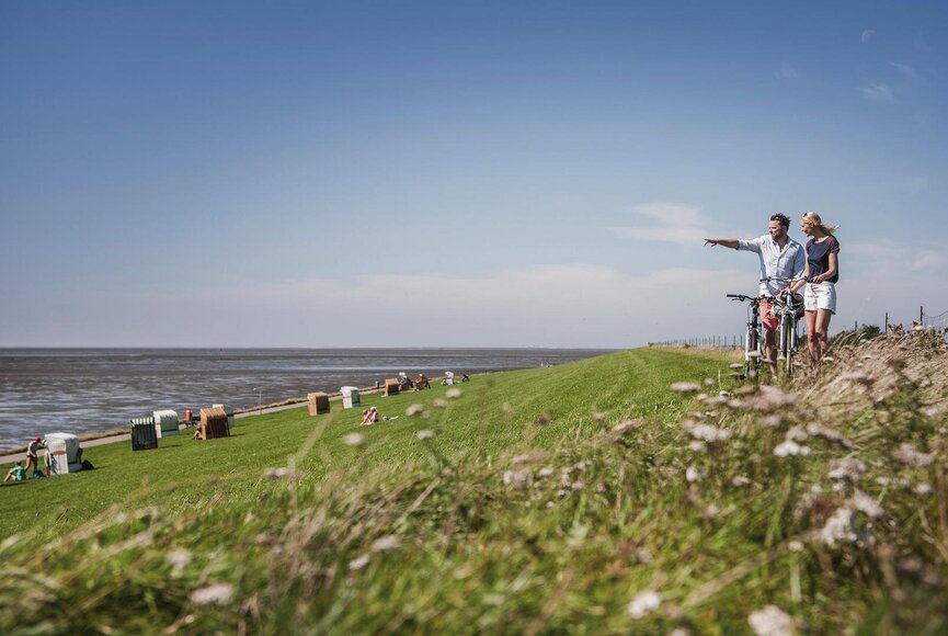 Paar mit Fahrrädern an der Badeecke in Vollerwiek am Deich