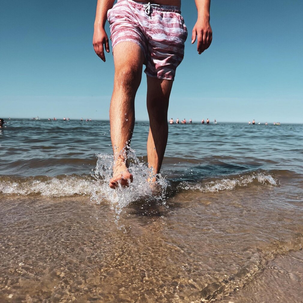 Mann läuft durch die Wellen am Strand