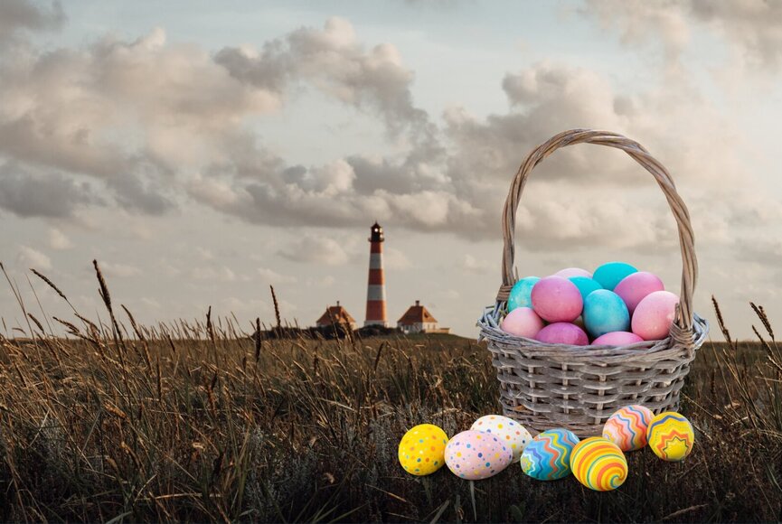 Korb mit bunten Ostereiern vor dem Westerhever Leuchtturm