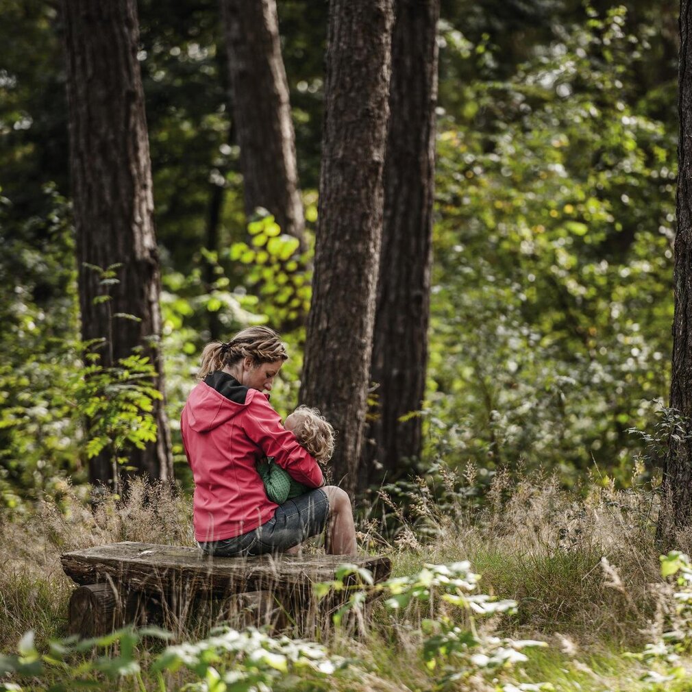 Frau mit Kind auf einer Bank im Wald