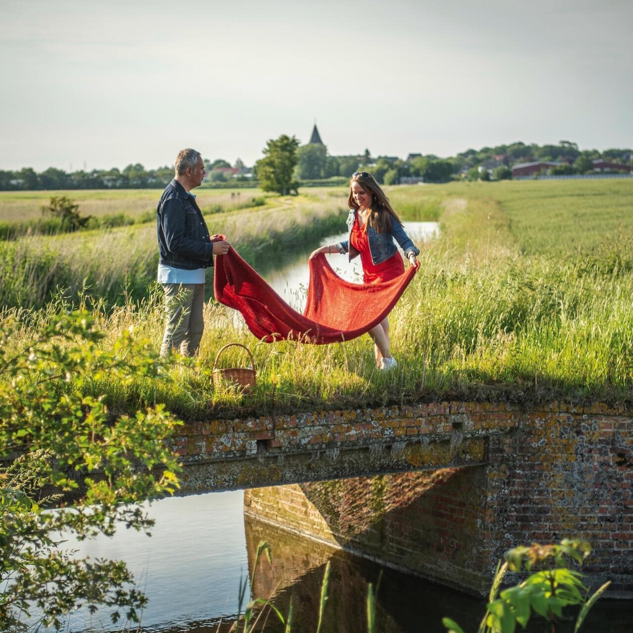 Pärchen breitet Picknickdecke auf einer Brücke aus