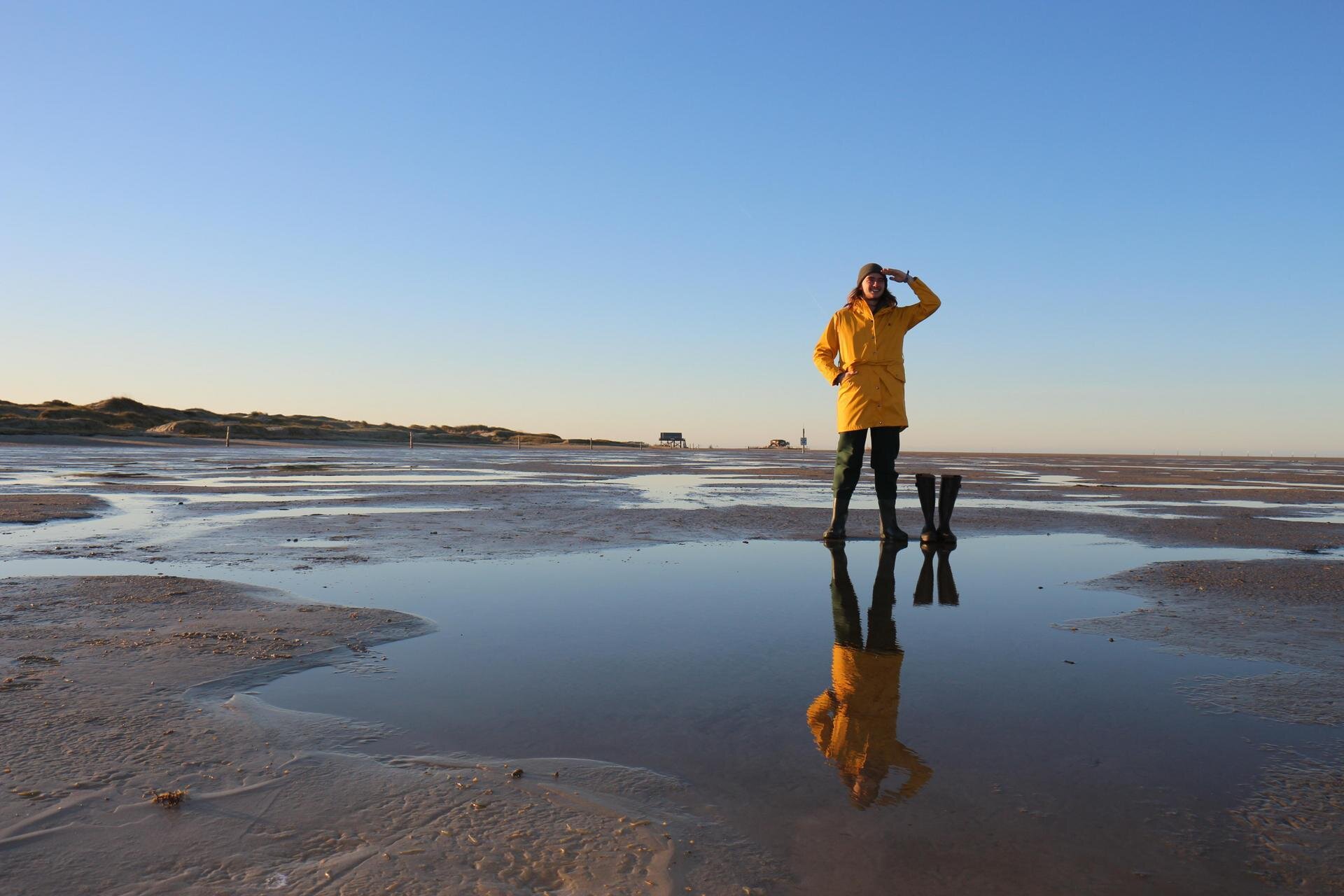sympathischer, junger Norddeutscher mit gelber Regenjacke und Gummistiefeln hält Aussicht am Ordinger Strand