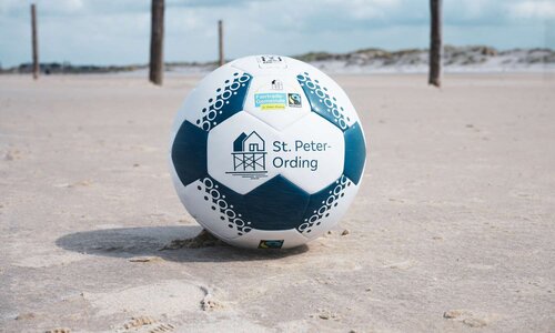 Ein Fußball mit St. Peter-Ording-Logo am Strand.
