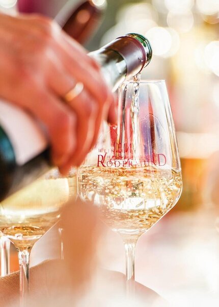 Weißwein wird aus einer Flasche in ein Glas eingeschenkt