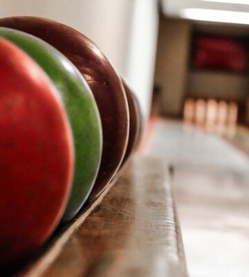 aufgereihte Kugeln zum Kegeln hintereinander mit Kegelbahn im Hintergrund