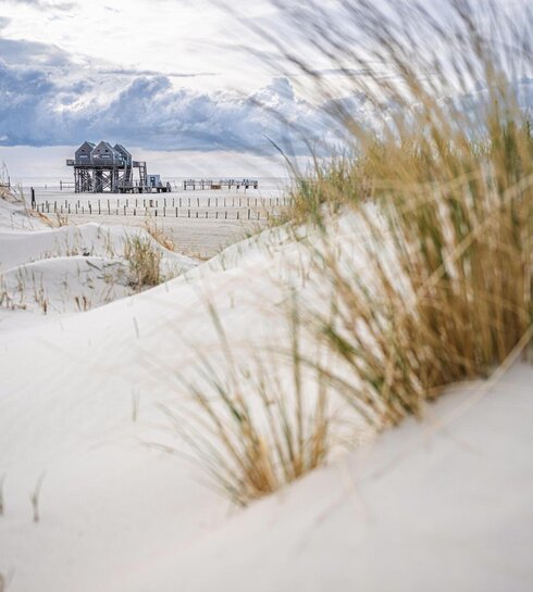 Blick durch die Dünen auf das Mehrzweckgebäude am Strand