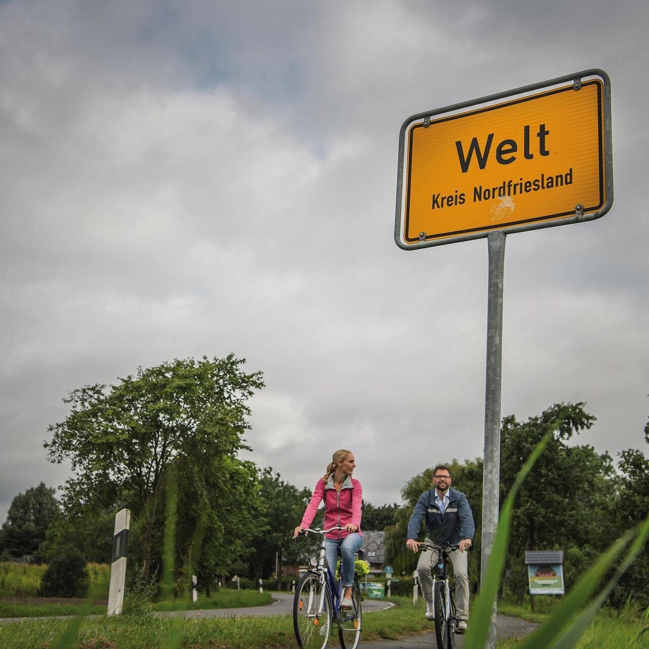 Pärchen auf Fahrradtour am Ortsschild Welt