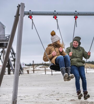 A couple on a swing at the beach