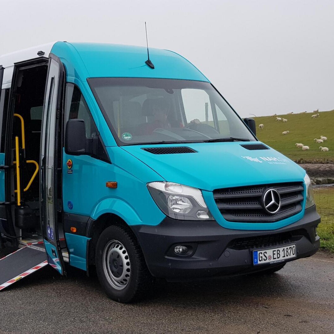 türkisfarbener Kleinbus mit offener Tür am Deich