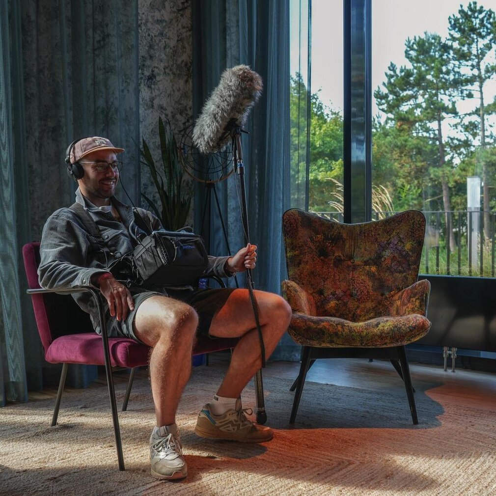 Der Tonmann sitzt auf einem Stuhl und hält das große Mikrofon