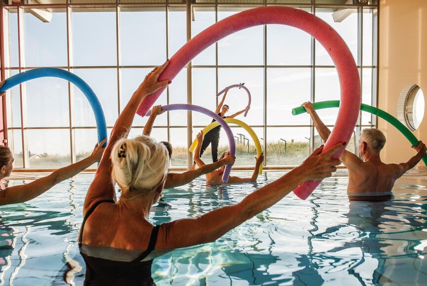 Gruppe bei Sportübungen mit Poolnudeln im Bewegungsbecken