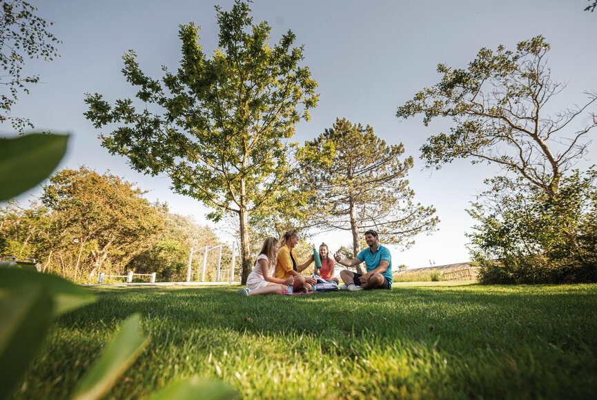 Familie picknickt auf dem Rasen an der Erlebnis-Promenade
