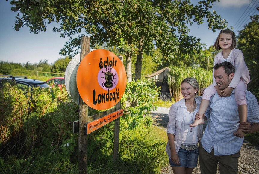 Familie vor dem Schild des Landcafes EClaire