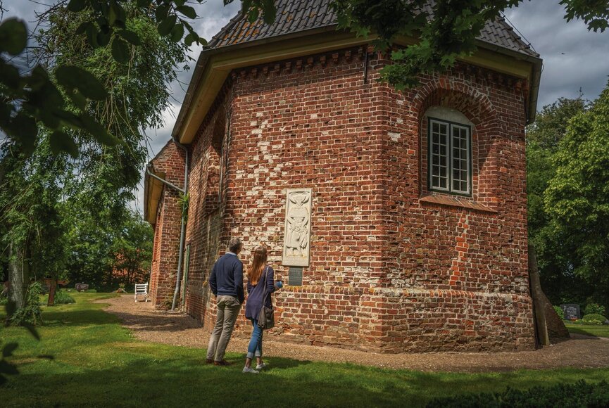 Paar betrachtet die außergewöhnliche Kirche in Katharinenheerd von außen