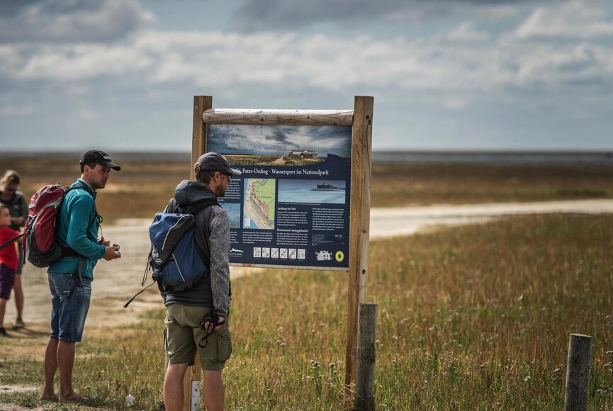 Besucher vor Infotafel am Südstrand