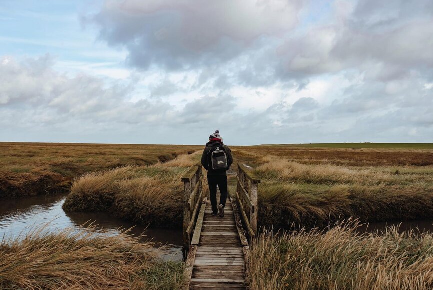 Mann auf einer Brücke auf einer Outdoor Escape Tour durch die Wiesenlandschaft
