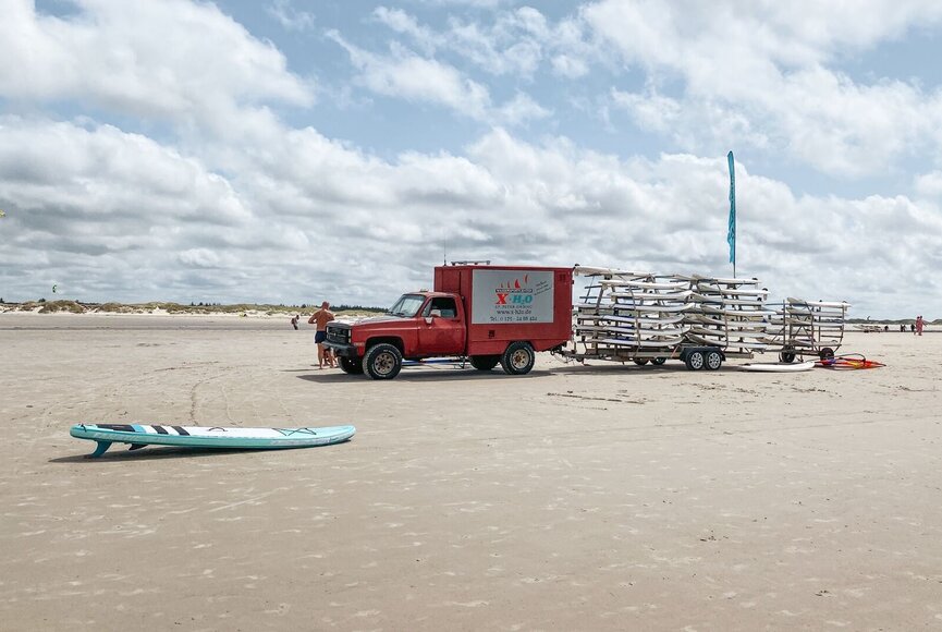 Auto vom Wassersportcenter XH2O mit Anhänger voller Surfbretter