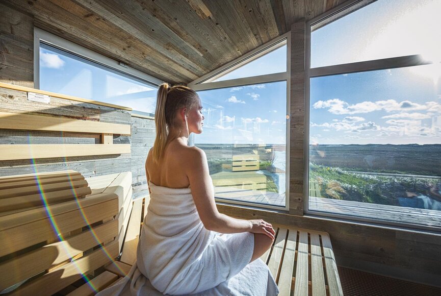 Frau entspannt in der Pfahlbausauna mit großem Panoramafenster