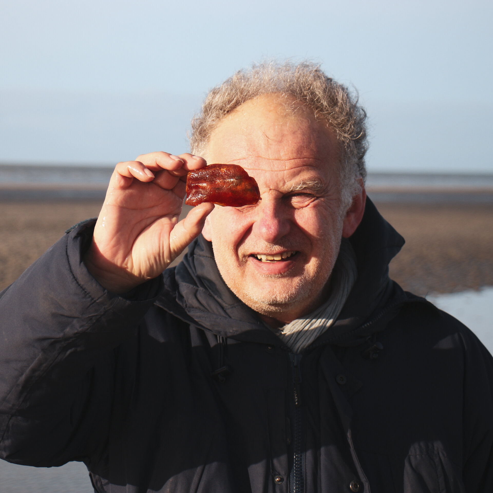 Boy Jöns vom Bernsteinmuseum schaut Bernstein am Strand an