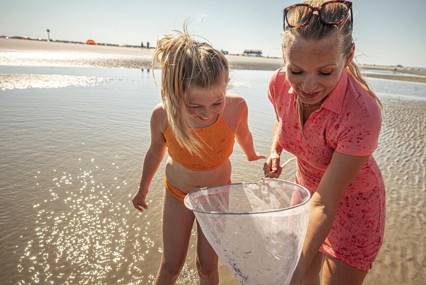 Mutter und Tochter mit Kescher an der Wasserkante