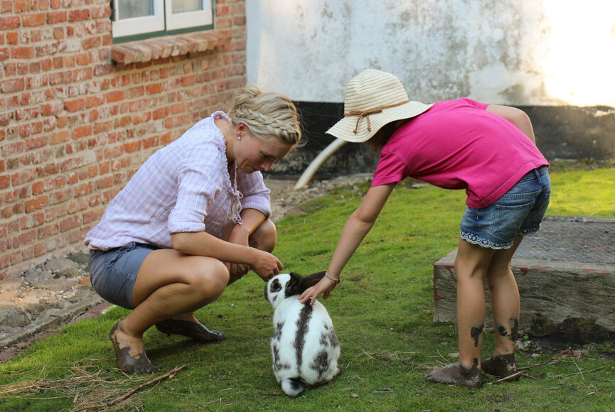 zwei Kinder streicheln einen Hasen auf dem Bauernhof in Welt