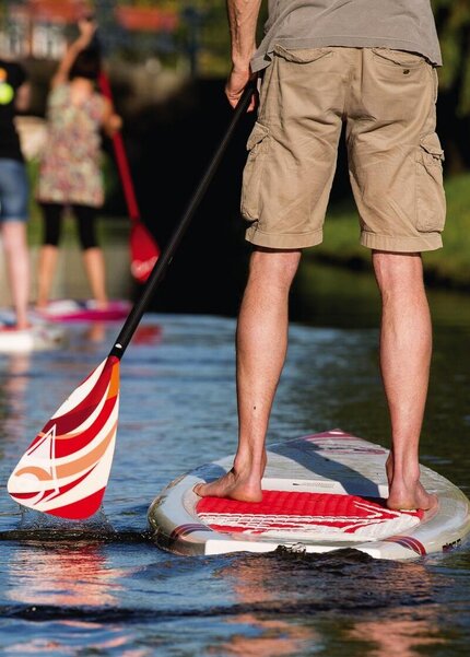 Menschen mit kurzen Hosen beim Stand-up-Paddling auf dem Wasser