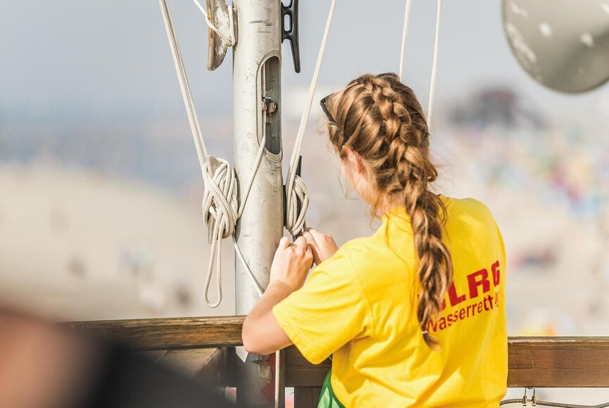 Frau der DLRG sichert die gehisste Fahne