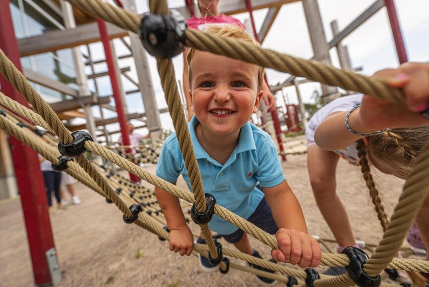 kleiner Junge am Toben auf dem Klettergerüst