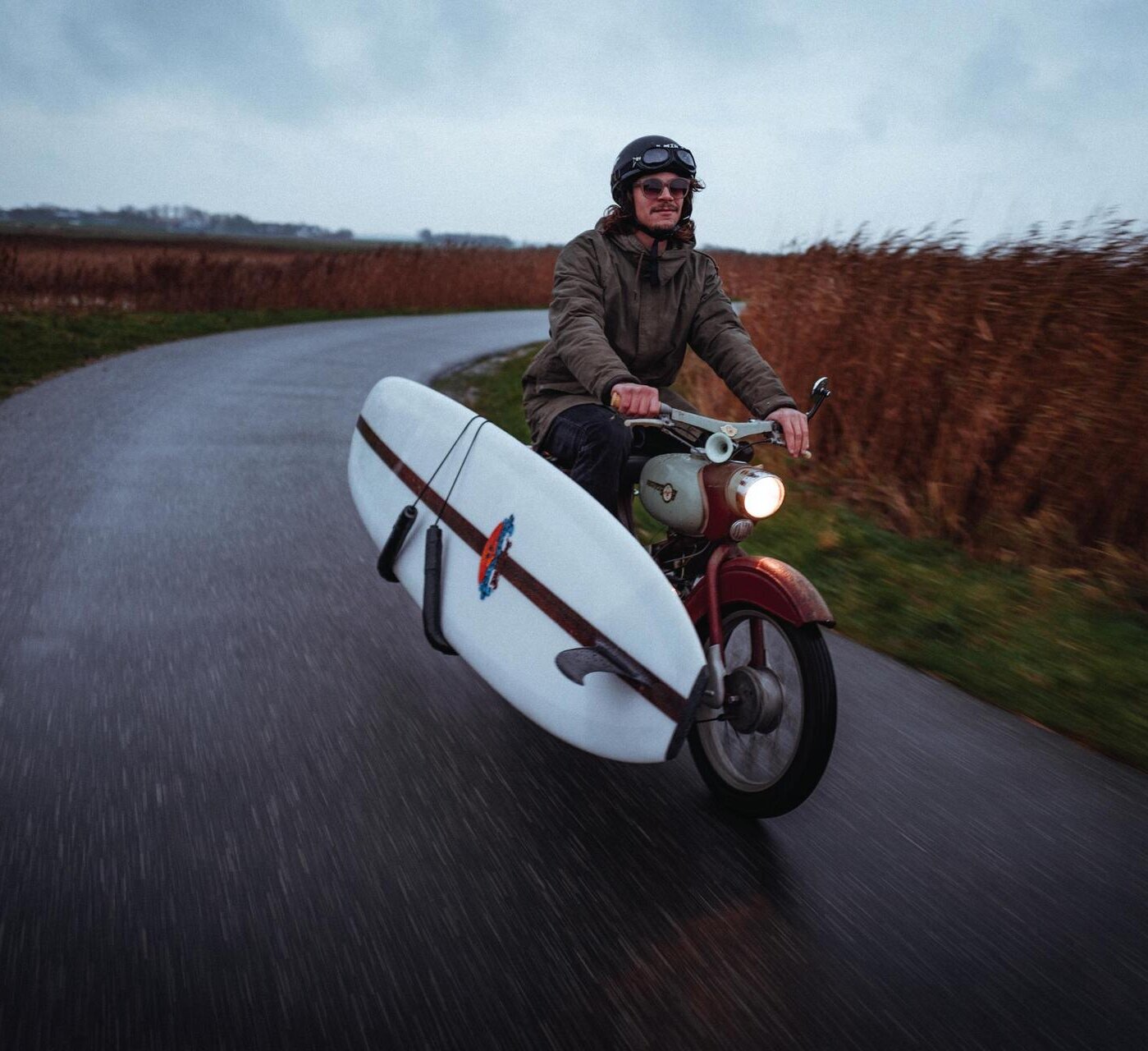 Surferboy mit Surfbrett auf Motorrad
