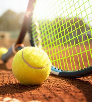 Tennisschläger und Tennisball auf einem Tennisplatz in der Sonne