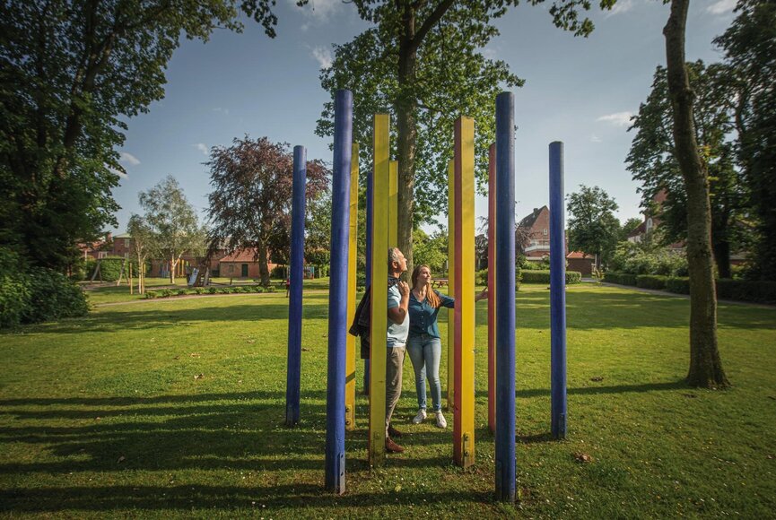Paar im grünen Stadtpark in Garding mit Spielplatz im Hintergrund