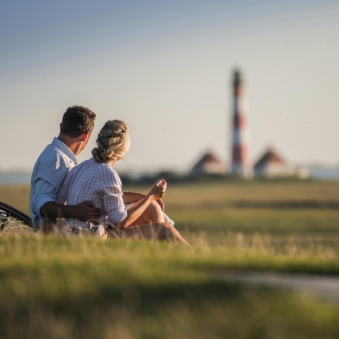 Pause eines Pärchens auf dem Deich mit Blick auf den Westerhever Leuchtturm
