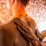 Rücken von einer Frau wird eingecremt