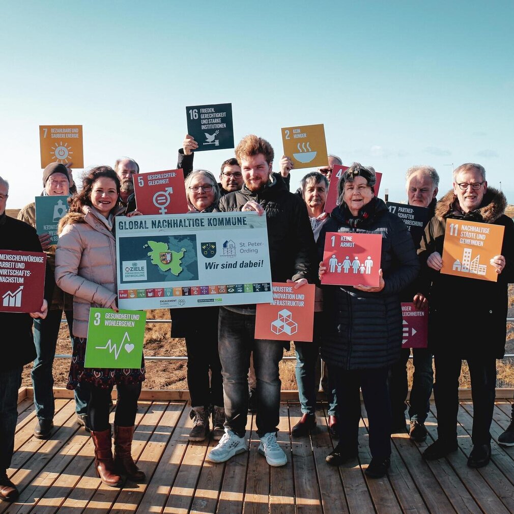 Menschen mit Schildern zu den 17 Zielen - St. Peter -Ording als Global Nachhaltige Kommune