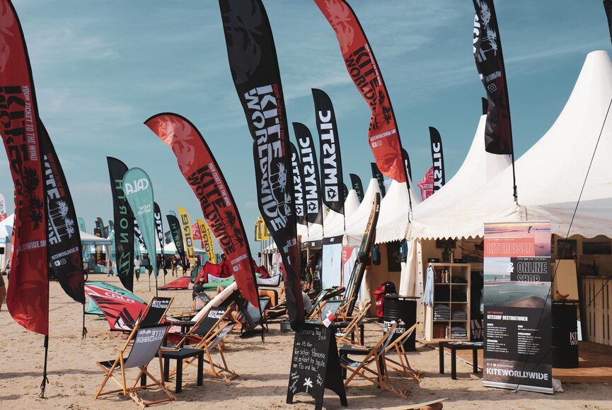 Auf dem Eventgelände am Strand während den Kitesurf Masters mit weißen Pagoden und bunten Beachflags