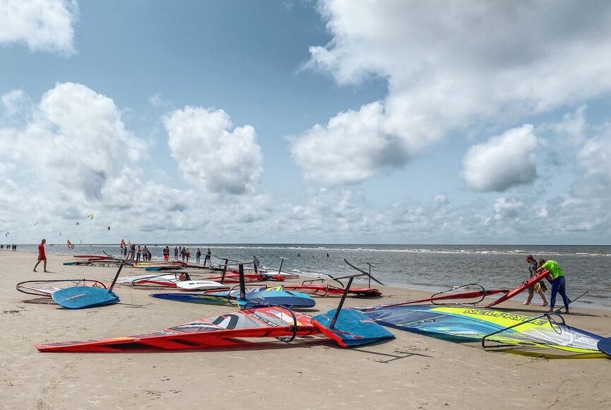 Windsurfbretter liegen an der Wasserkante am Strand