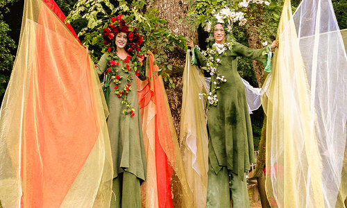 Riesengroße Feen in grünen Gewändern und Blumen auf dem Kopf.