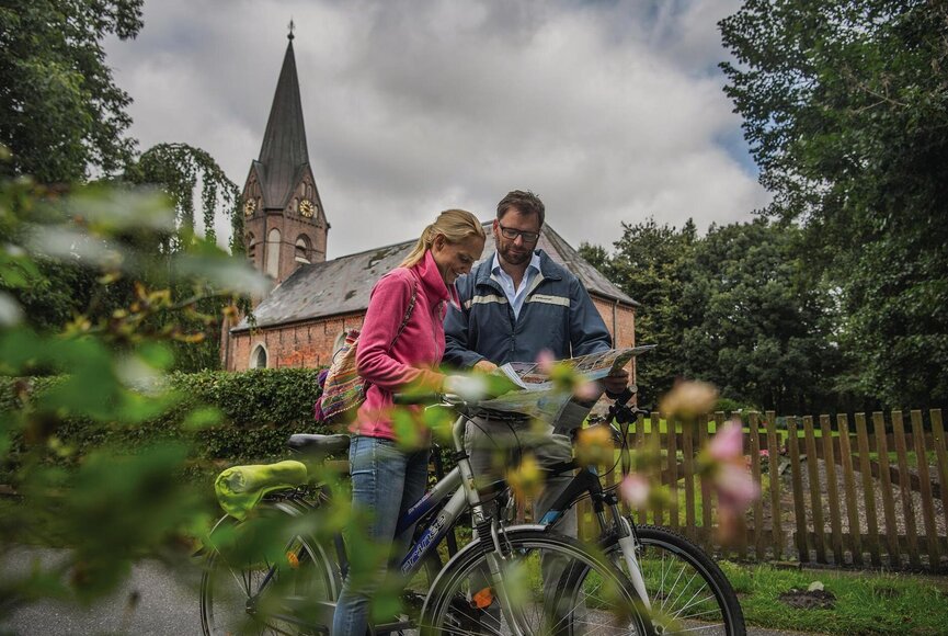 Pärchen mit Fahrrad vor der Sommerkirche in Welt 