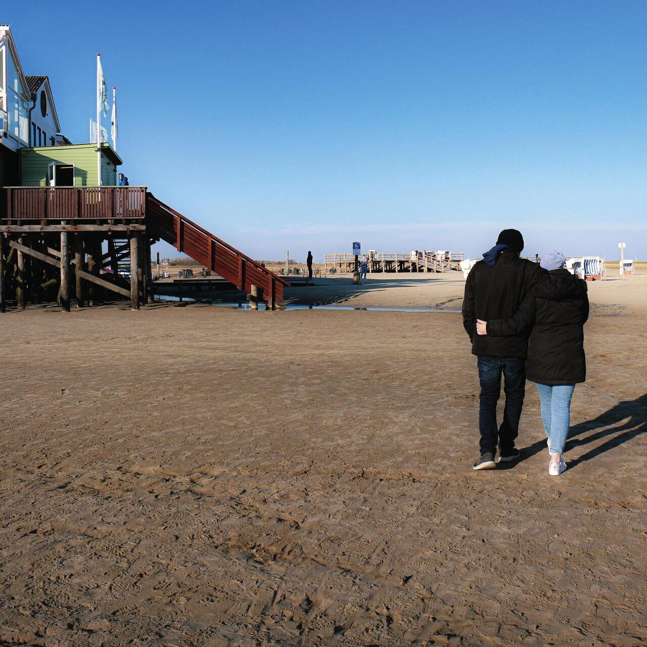 Spaziergang eines Paares am Böhler Strand unter blauem Himmel