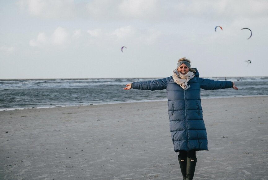 sympathische, junge Norddeutsche am Sandstrand mit Drachen im Hintergrund